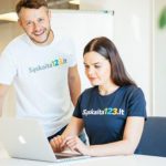 Laisvai samdomas specialistas dirba nešiojamuoju kompiuteriu šiuolaikiškoje darbo erdvėje su miesto panorama.