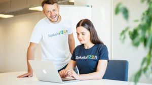 Vilnius, Kaunas ar Klaipėda – kuriame mieste freelanceriui geriausia? Laisvai samdomas specialistas dirba nešiojamuoju kompiuteriu šiuolaikiškoje darbo erdvėje su miesto panorama.