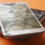 Ant grindų nukritęs telefonas su sudužusiu ekranu po stipraus smūgio