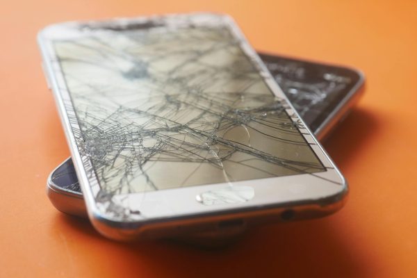 Ant grindų nukritęs telefonas su sudužusiu ekranu po stipraus smūgio