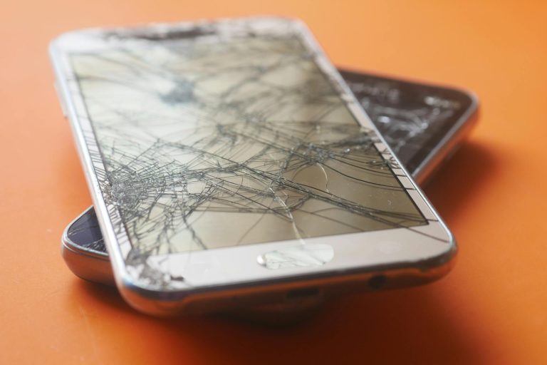 Ant grindų nukritęs telefonas su sudužusiu ekranu po stipraus smūgio